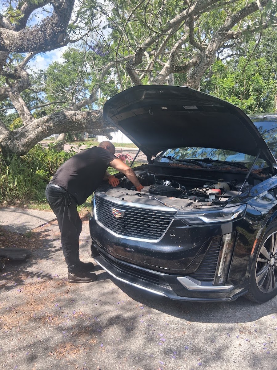 Mechanic doing brake work on a white GMC Terrain with tire removed